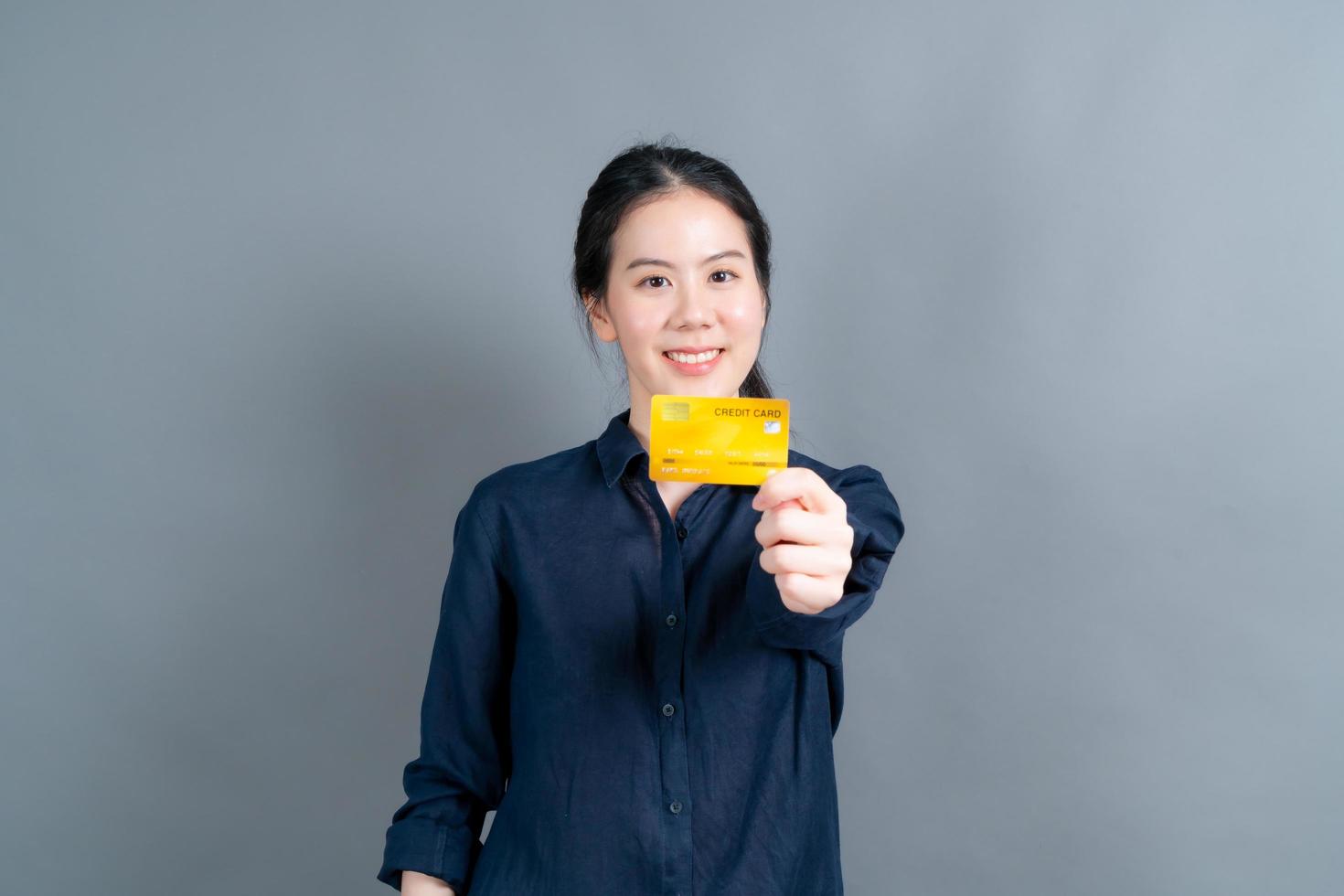 retrato de uma adorável jovem asiática mostrando cartão de crédito foto