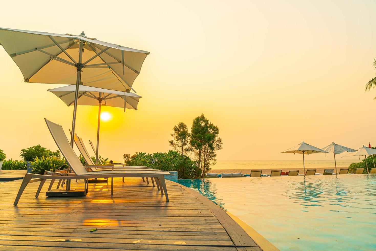 guarda-sol e cadeira ao redor da piscina com vista para o mar foto