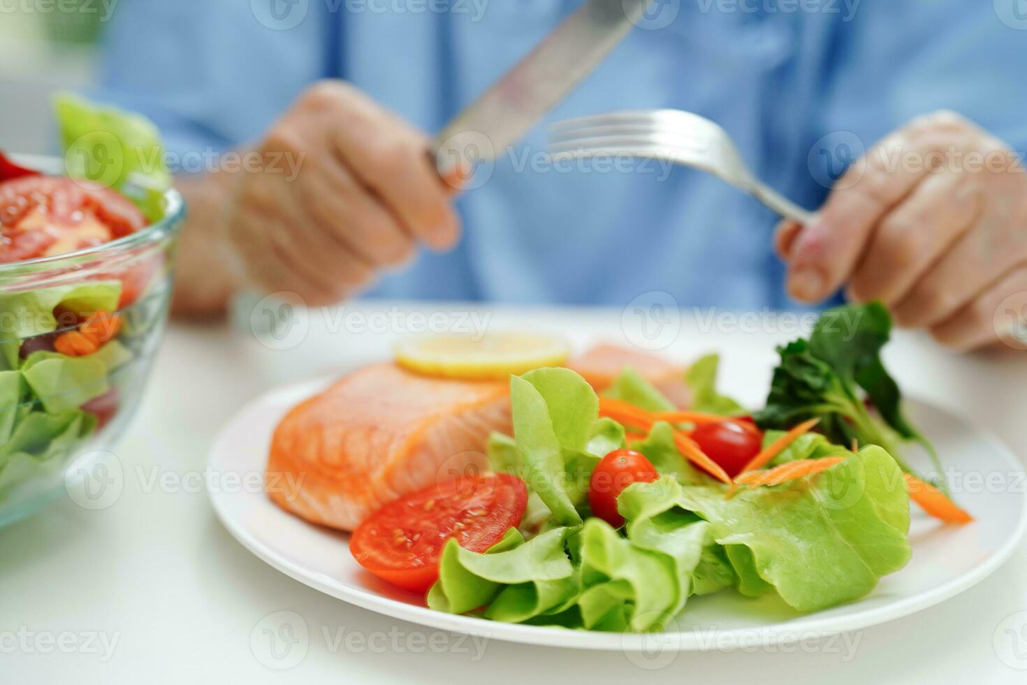 ásia idosos mulher paciente comendo salmão estaca e vegetal salada para saudável Comida dentro hospital. foto