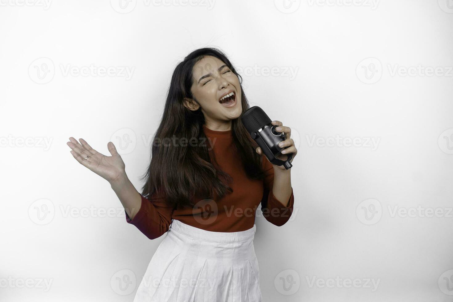 retrato de mulher asiática despreocupada, se divertindo karaokê, cantando no microfone em pé sobre fundo branco foto