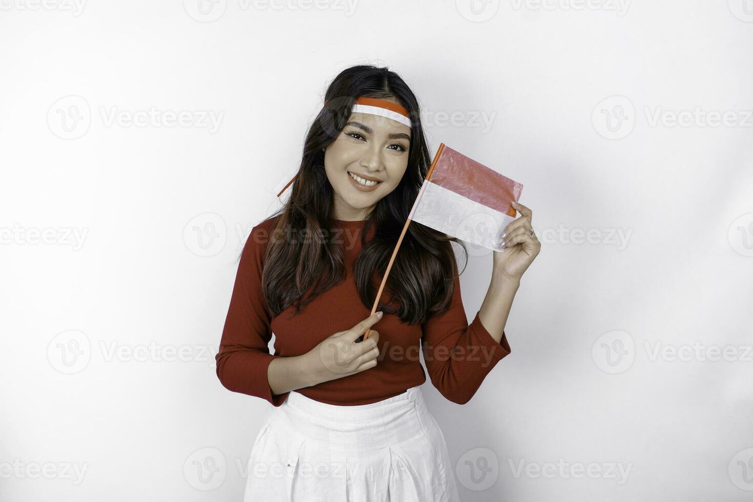 animado jovem ásia mulher comemoro indonésio independência dia segurando a indonésio bandeira isolado em branco fundo foto