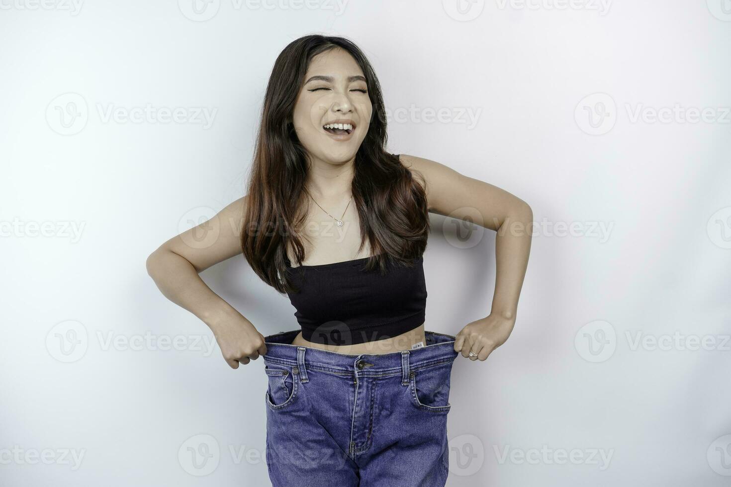 dieta e peso perda conceito. uma jovem ásia mulher dentro de grandes dimensões jeans isolado em uma branco fundo. foto