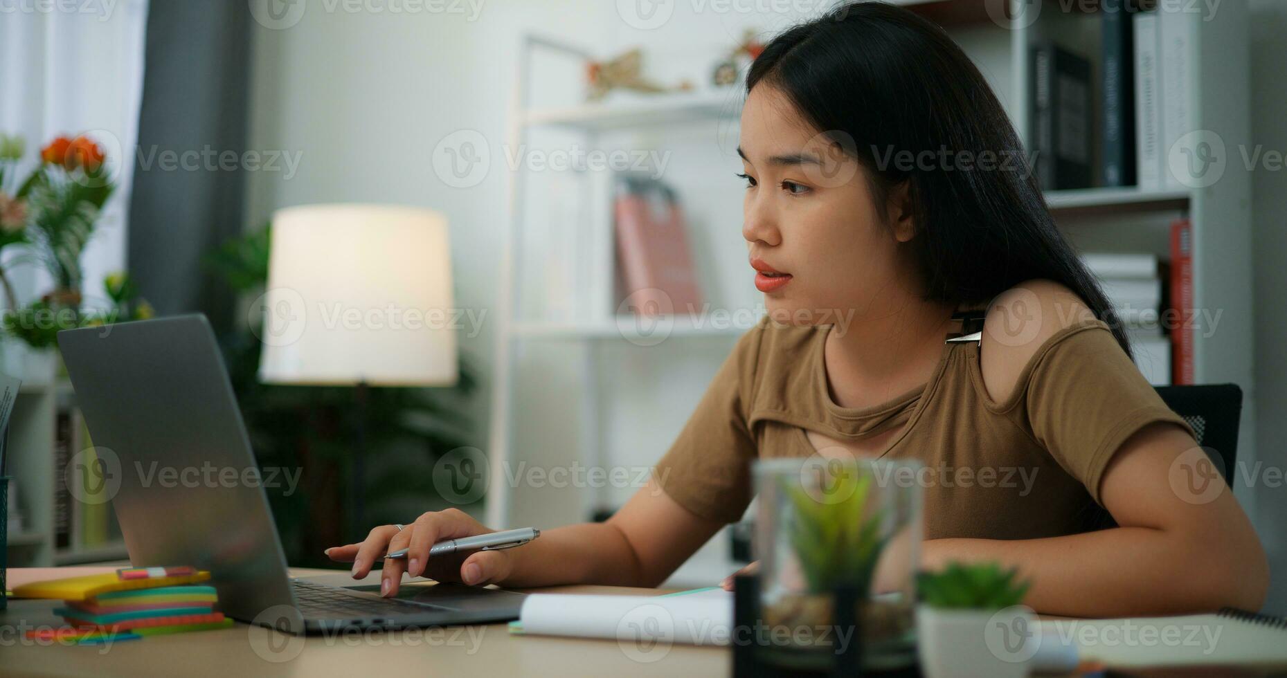 jovem ásia mulher trabalhando com uma computador portátil em uma escrivaninha foto