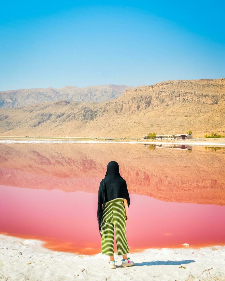 mulher caucasiana assistir maharlu pink salt lake panorama em shiraz, irã. foto