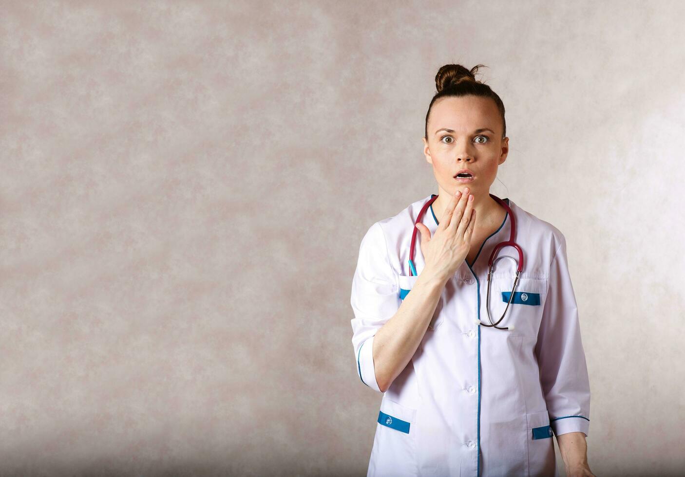 jovem fêmea médico vestido dentro uma branco médico uniforme tem uma assustado expressão do uma face. foto