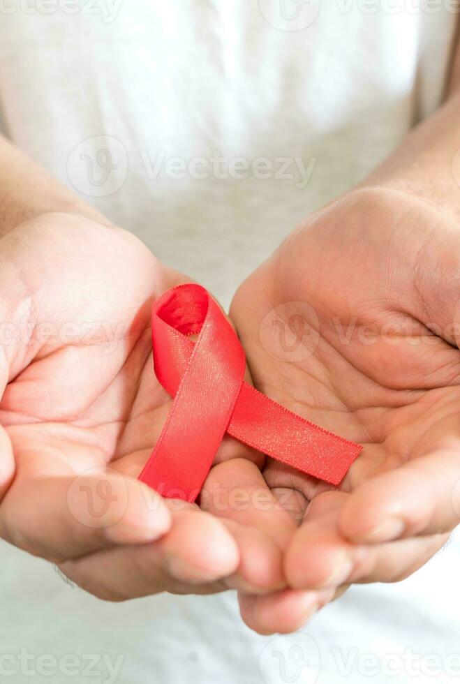 mundo Auxilia dia, ajuda vermelho fita dentro mãos em uma de madeira fundo foto