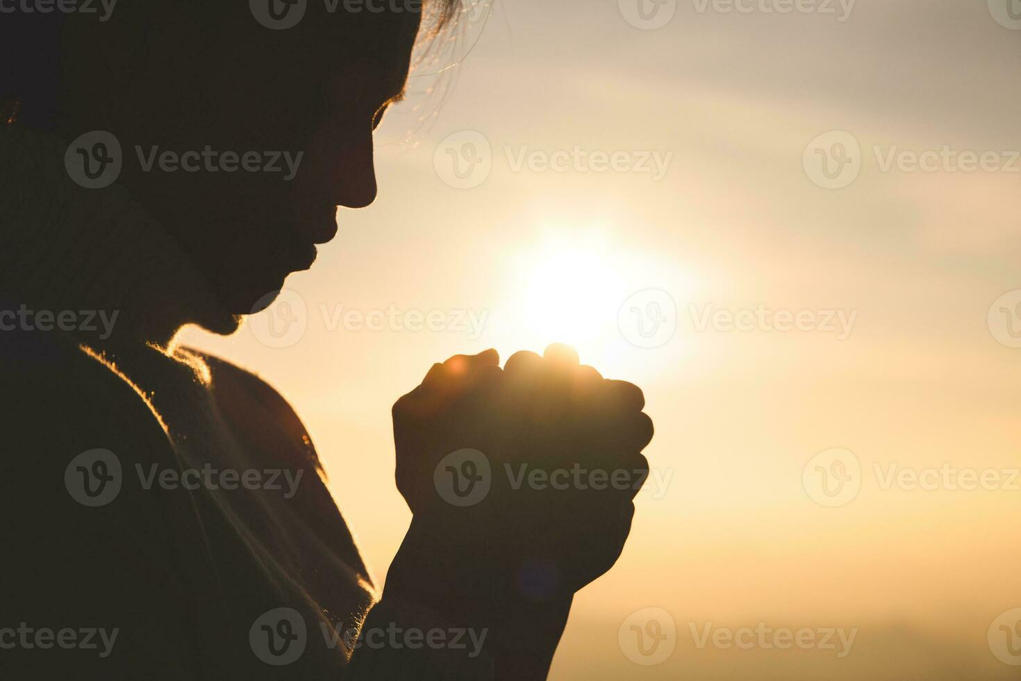 silhueta de uma mulher com as mãos levantadas no conceito de pôr do sol para religião, adoração, oração e louvor, conceitos religiosos foto