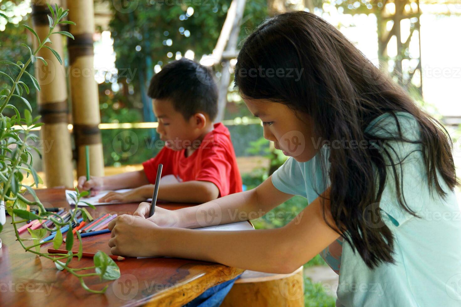 ásia crianças estão feliz para desenhar seus imaginações e pintura com giz de cera dentro seus poupar Tempo às casa durante escola feriados. suave e seletivo foco. foto