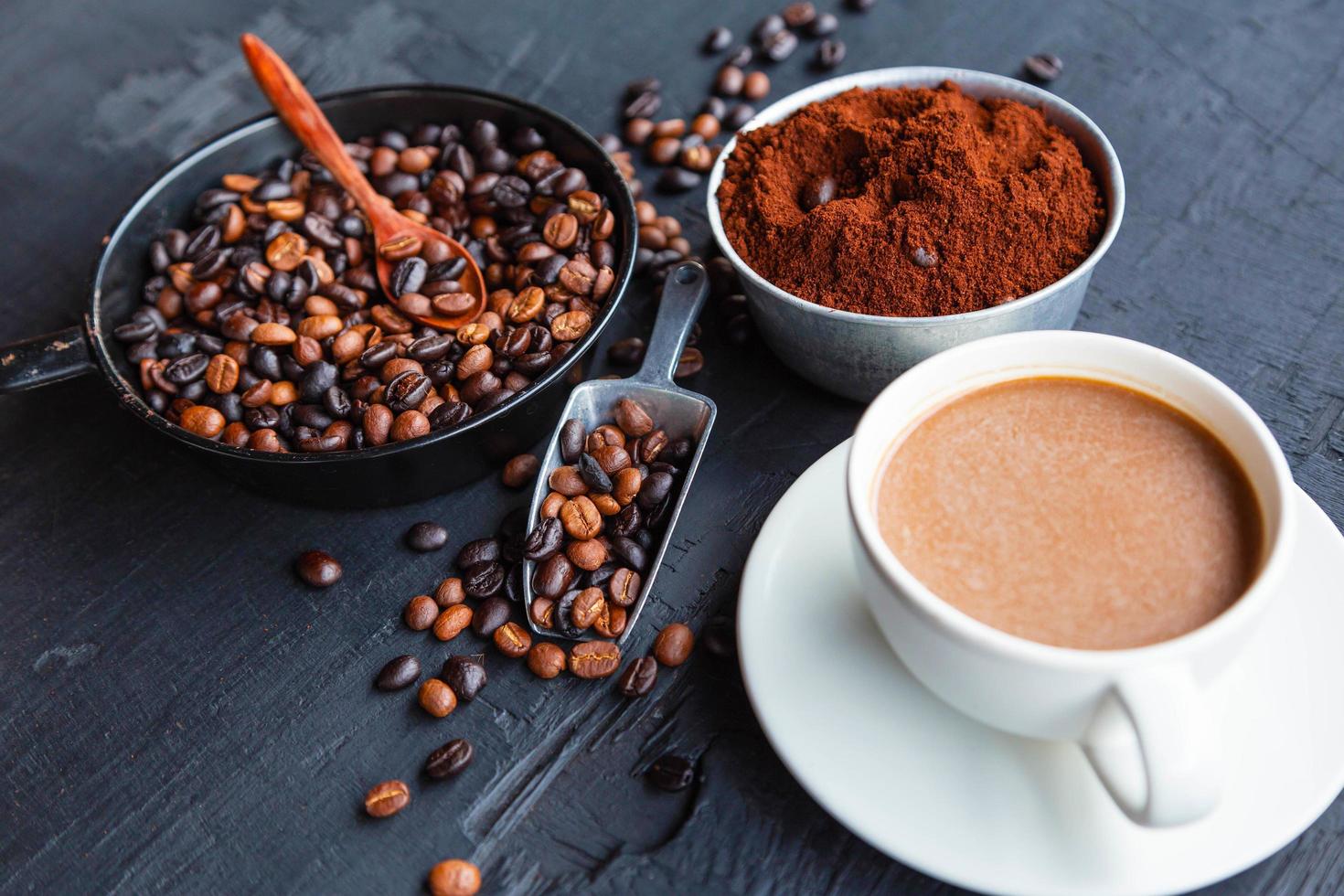 grãos de café torrados com pó de café e xícaras de café. foto