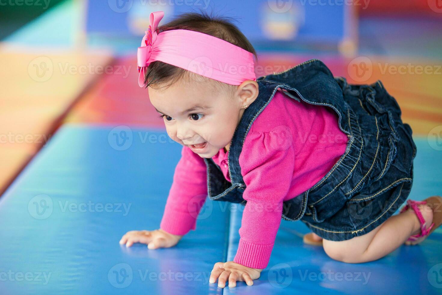 lindo dez meses bebê menina rastejando em uma colorida fundo. cedo estimulação para crianças conceito. foto