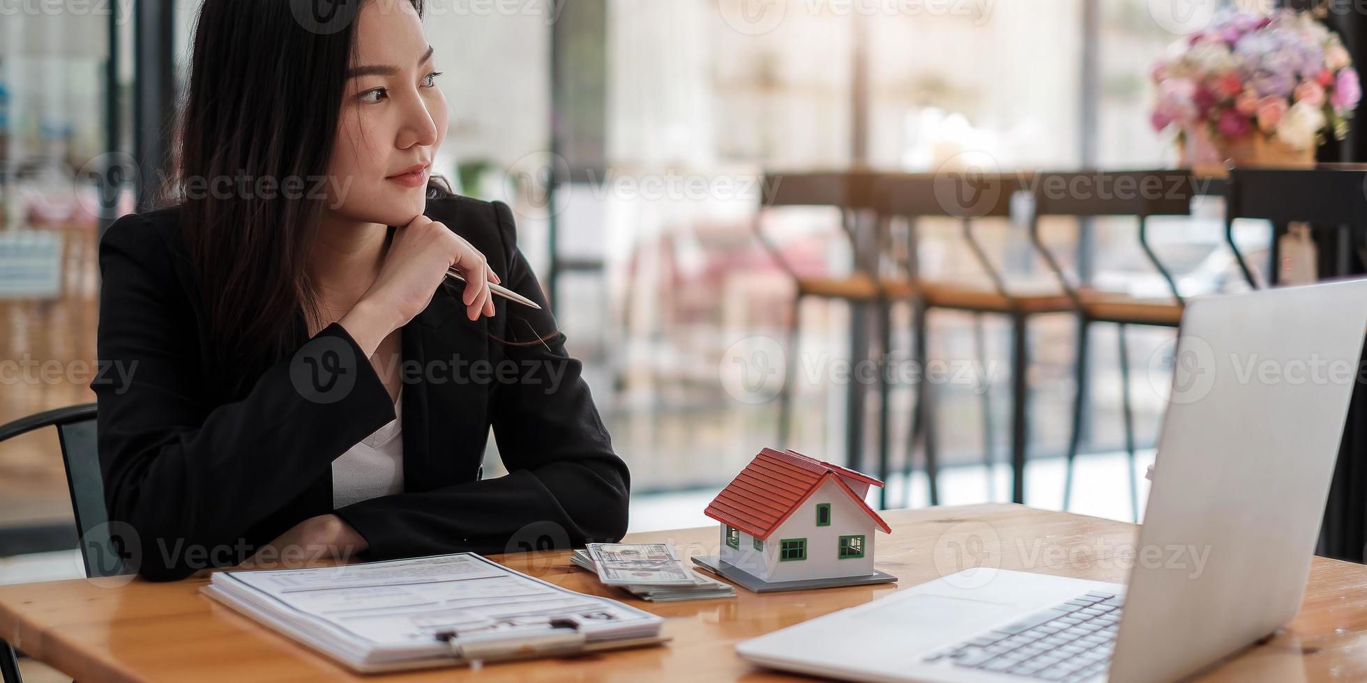 imagem recortada de agente imobiliário auxiliando o cliente a assinar o papel do contrato na mesa com a maquete da casa foto