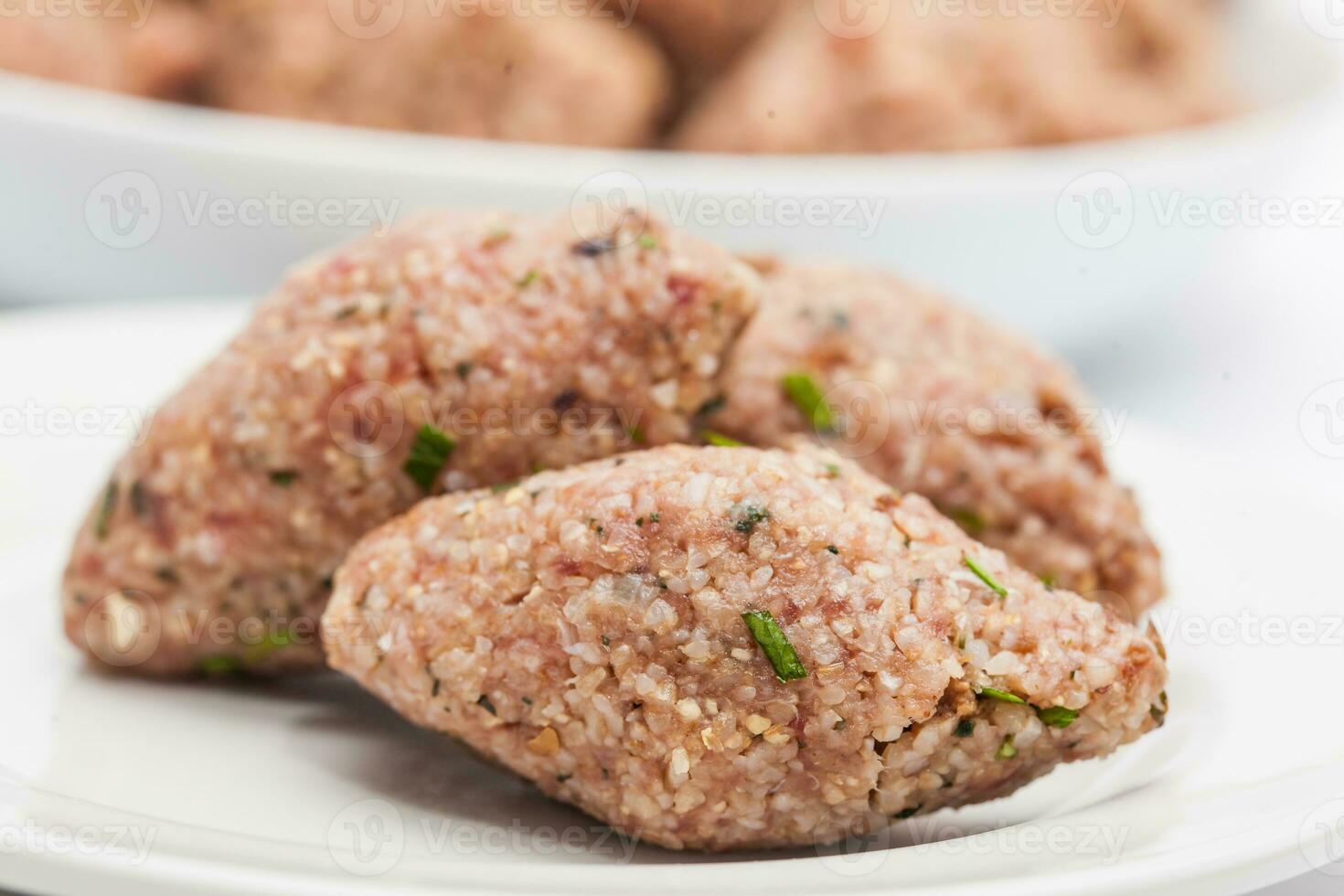 degrau de degrau levantine cozinha quibe preparação. cru quibe bolas em branco prato foto