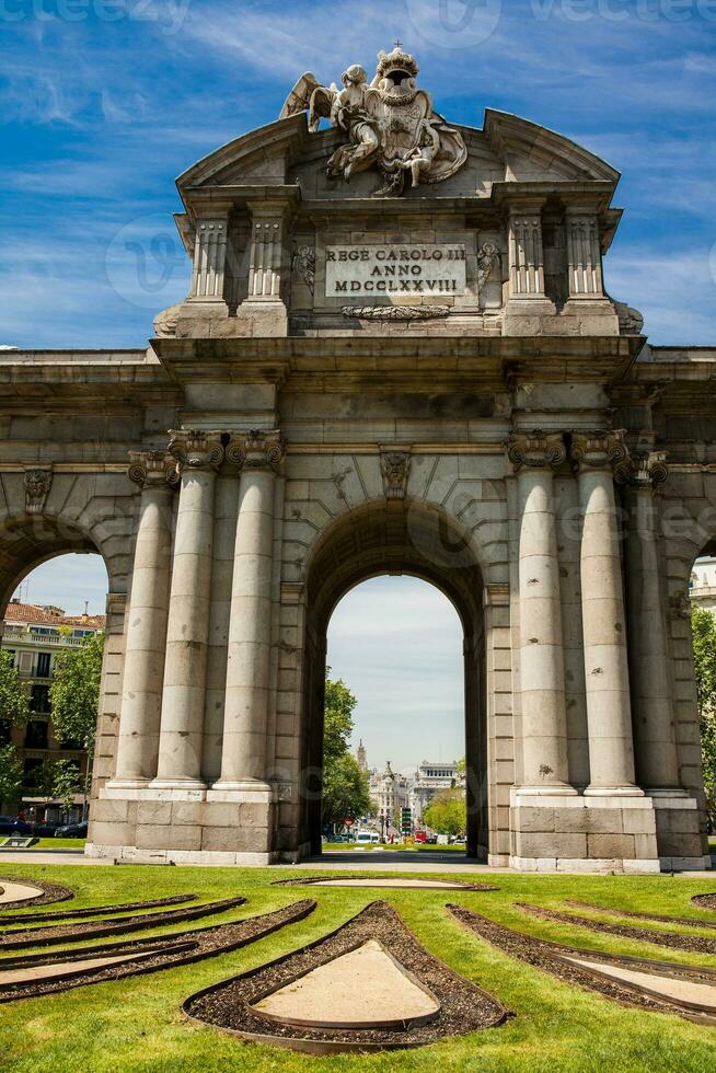 a famoso puerta de Alcala em uma lindo ensolarado dia dentro madri cidade. inscrição em a frontão rei carlos iii ano 1778 foto