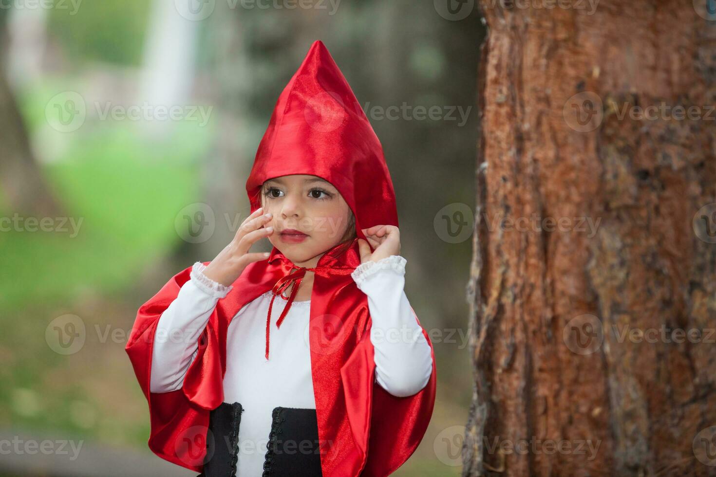 doce menina vestindo uma pequeno vermelho equitação de capuz fantasia. real família tendo Diversão enquanto usando fantasias do a pequeno vermelho equitação de capuz conto dentro dia das Bruxas. foto