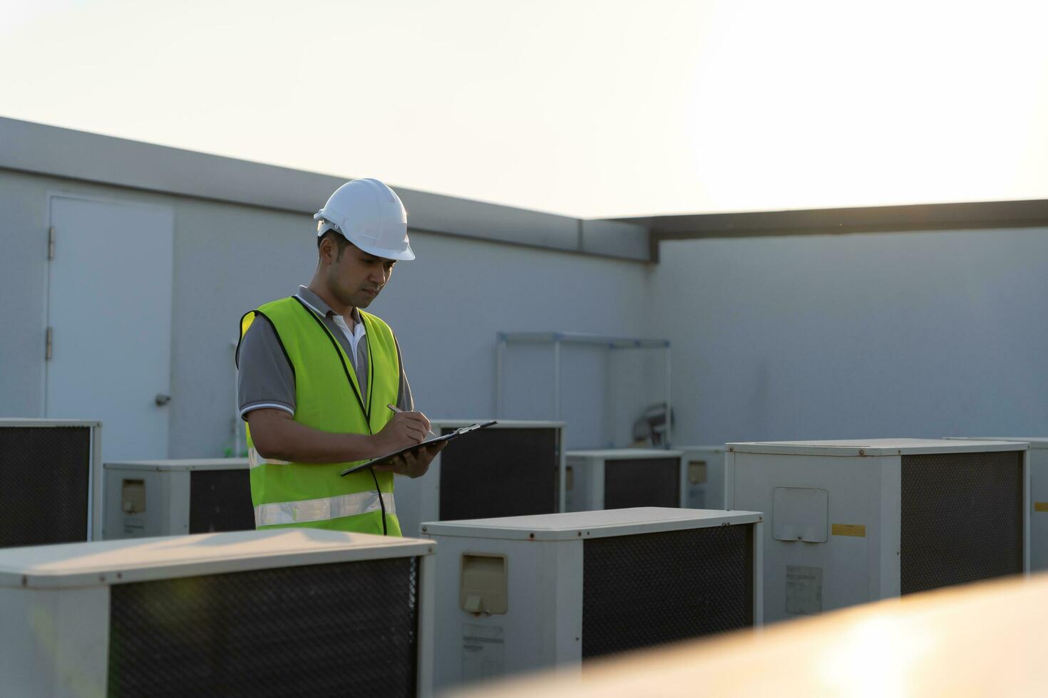 ásia manutenção engenheiro trabalho em a cobertura do fábrica. contratante inspecionar compressor sistema e planos instalação do ar condição sistemas dentro construção. lista de controle, inspetor, ao controle foto