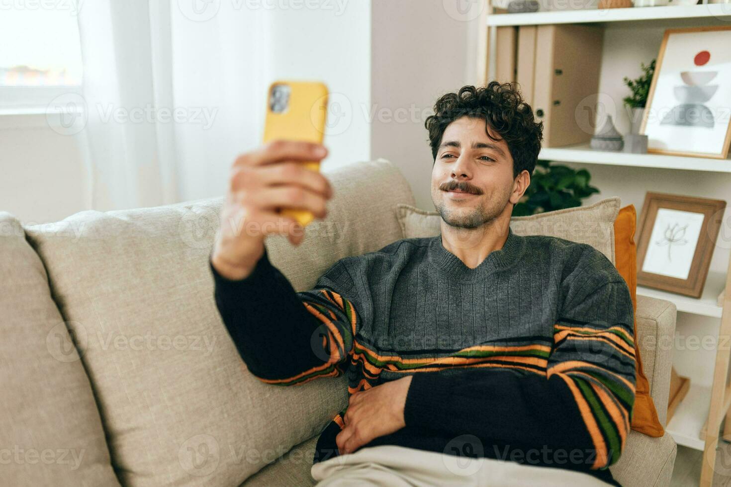 olhando homem tecnologia mensagem sofá telefone digitando selfie comunicação estilo de vida casa moderno cara sofá foto