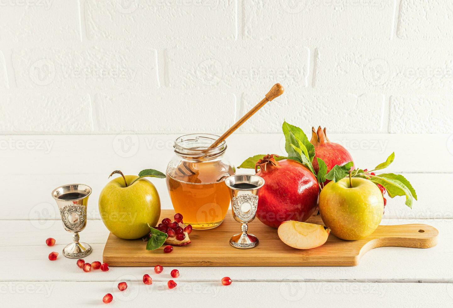 uma jarra do querida e fuso em uma de madeira borda com maduro frutas, romãs e maçãs tradicional Comida para a feriado do rosh hashaná. frente Visão foto