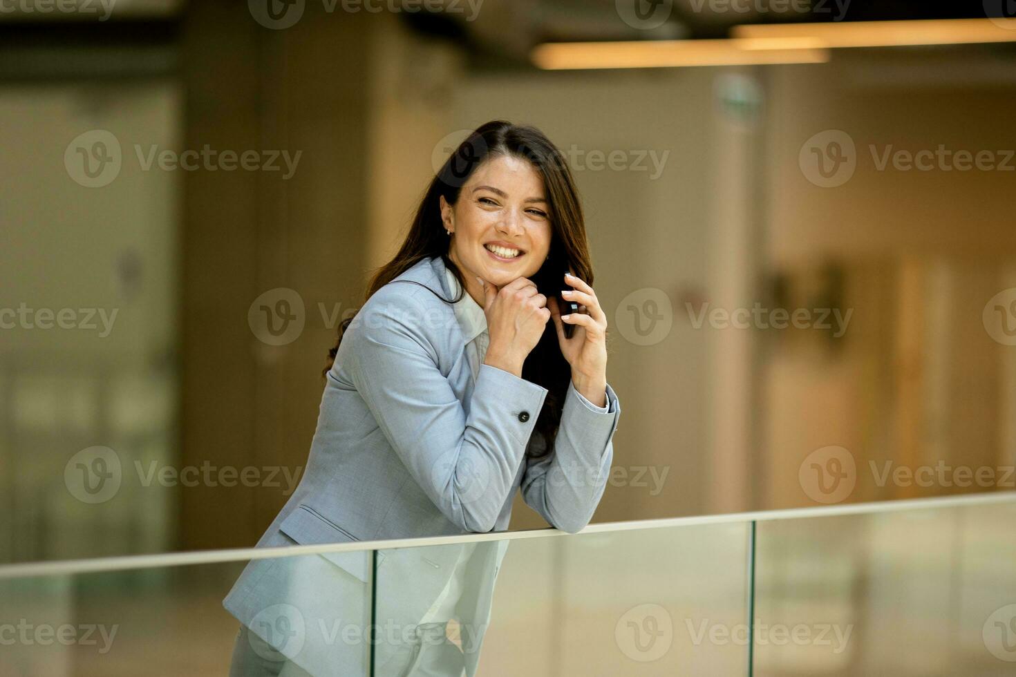 jovem o negócio mulher usando Móvel telefone dentro a escritório corredor foto