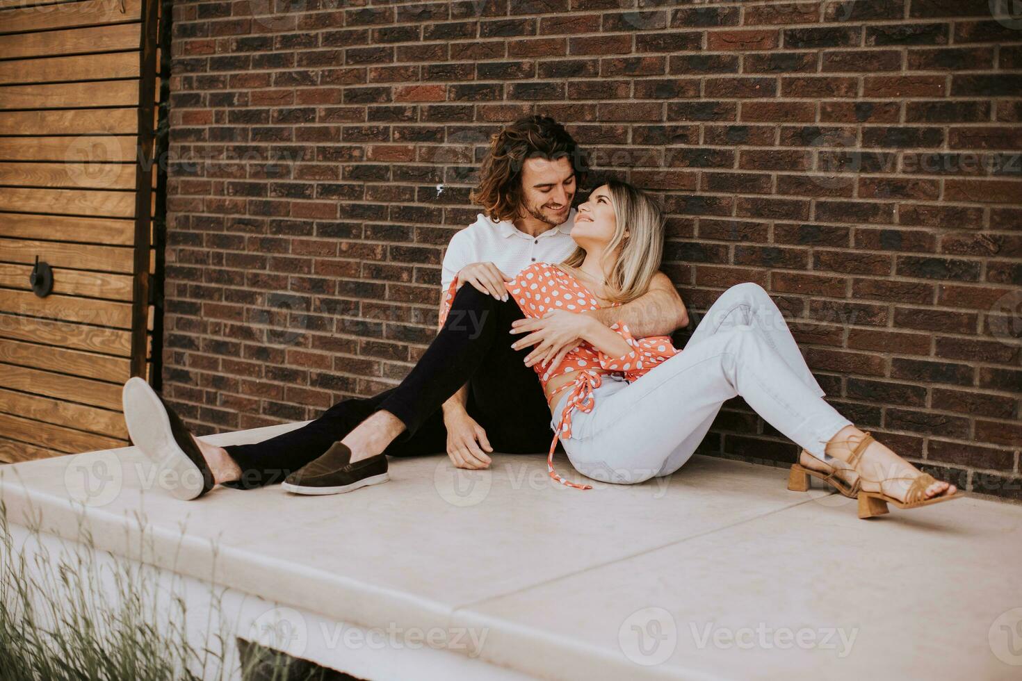 sorridente jovem casal dentro amor dentro frente do casa tijolo parede foto