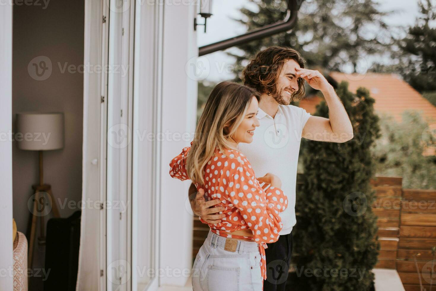 sorridente jovem casal dentro amor olhando dentro frente do casa tijolo parede foto