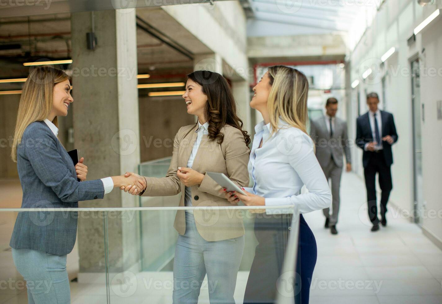 três jovem o negócio mulheres tendo uma discussão dentro a escritório corredor foto