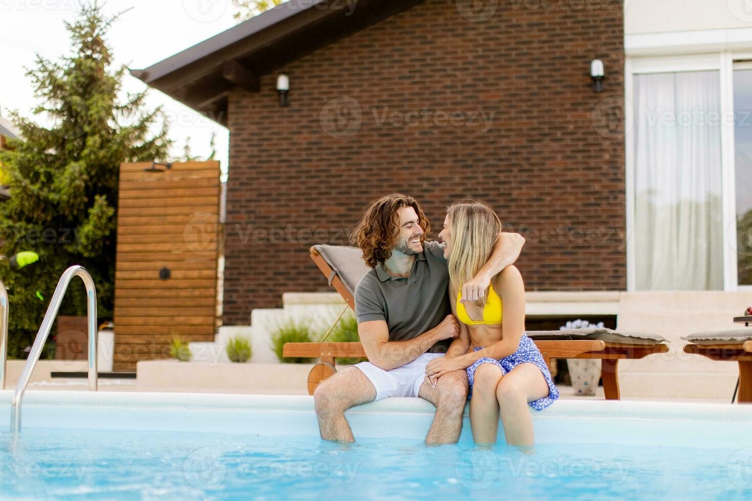 jovem casal relaxante de a natação piscina dentro a casa quintal foto