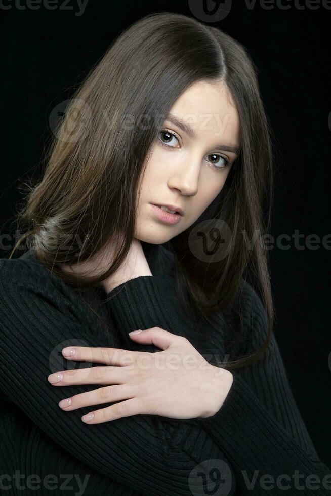 vertical retrato do uma lindo dezessete ano velho menina com grandes cabelo contra uma Sombrio fundo. foto