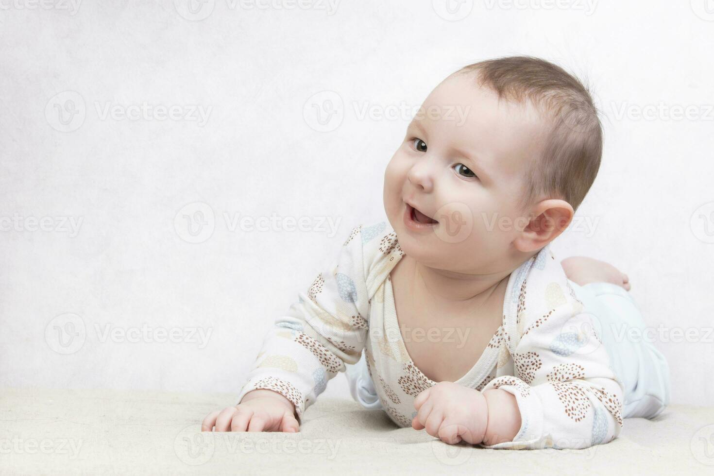 criança com uma sorrir em uma branco fundo. a adorável seis mês velho bebê Garoto é deitado em a cama. conceptual foto do paternidade e maternidade.