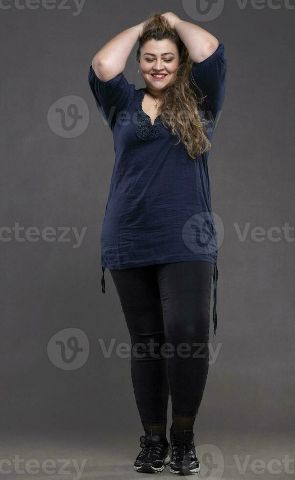 lindo gordo mulher em uma cinzento fundo. foto