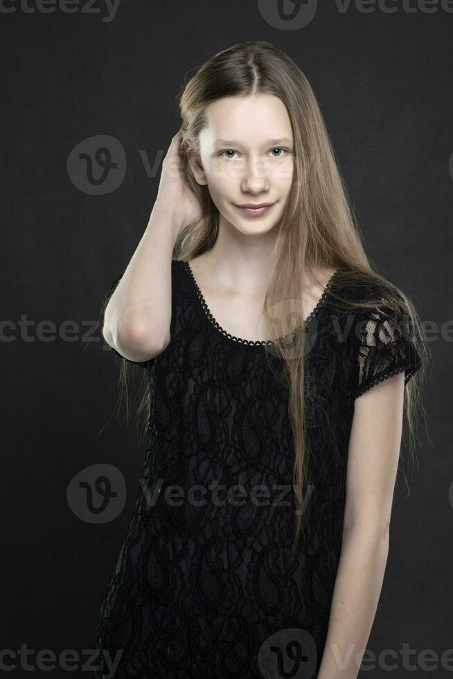 retrato do uma lindo Adolescência menina é tiro contra uma cinzento fundo. fino menina Loiras com azul olhos. foto