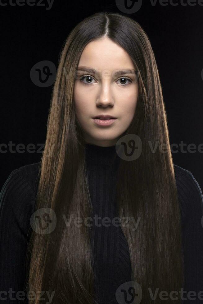 lindo morena menina com grandes cabelo em uma Preto fundo. dezessete anos mulher. clássico retrato do uma jovem garota. foto