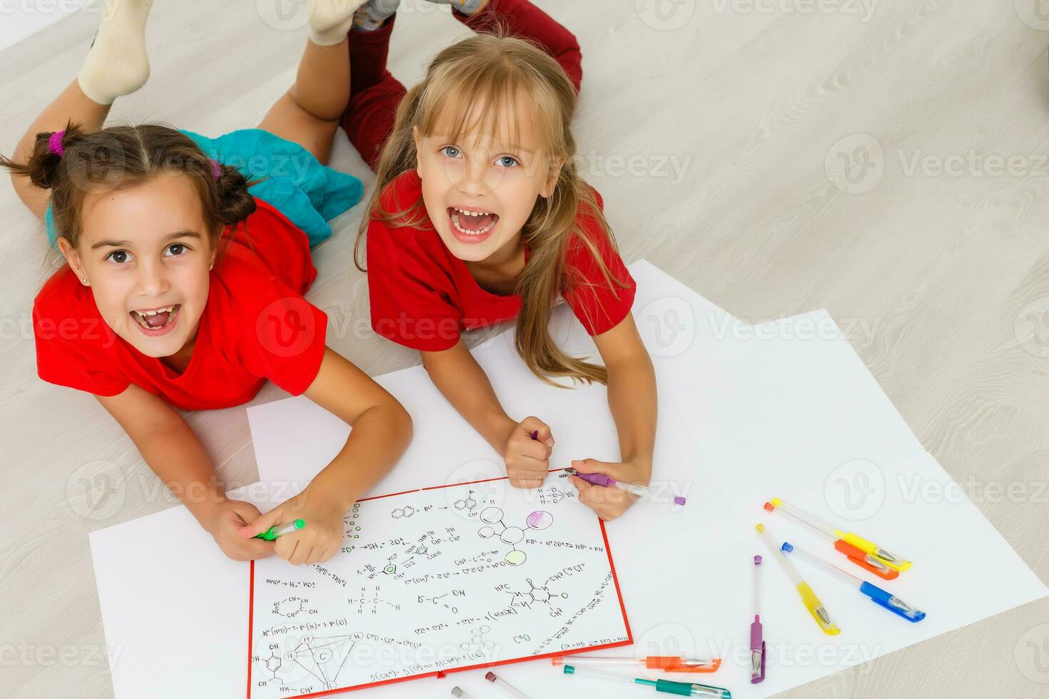 família, lazer e infância conceito - feliz irmãs deitado em chão e desenhando e fazendo dever de casa às casa foto