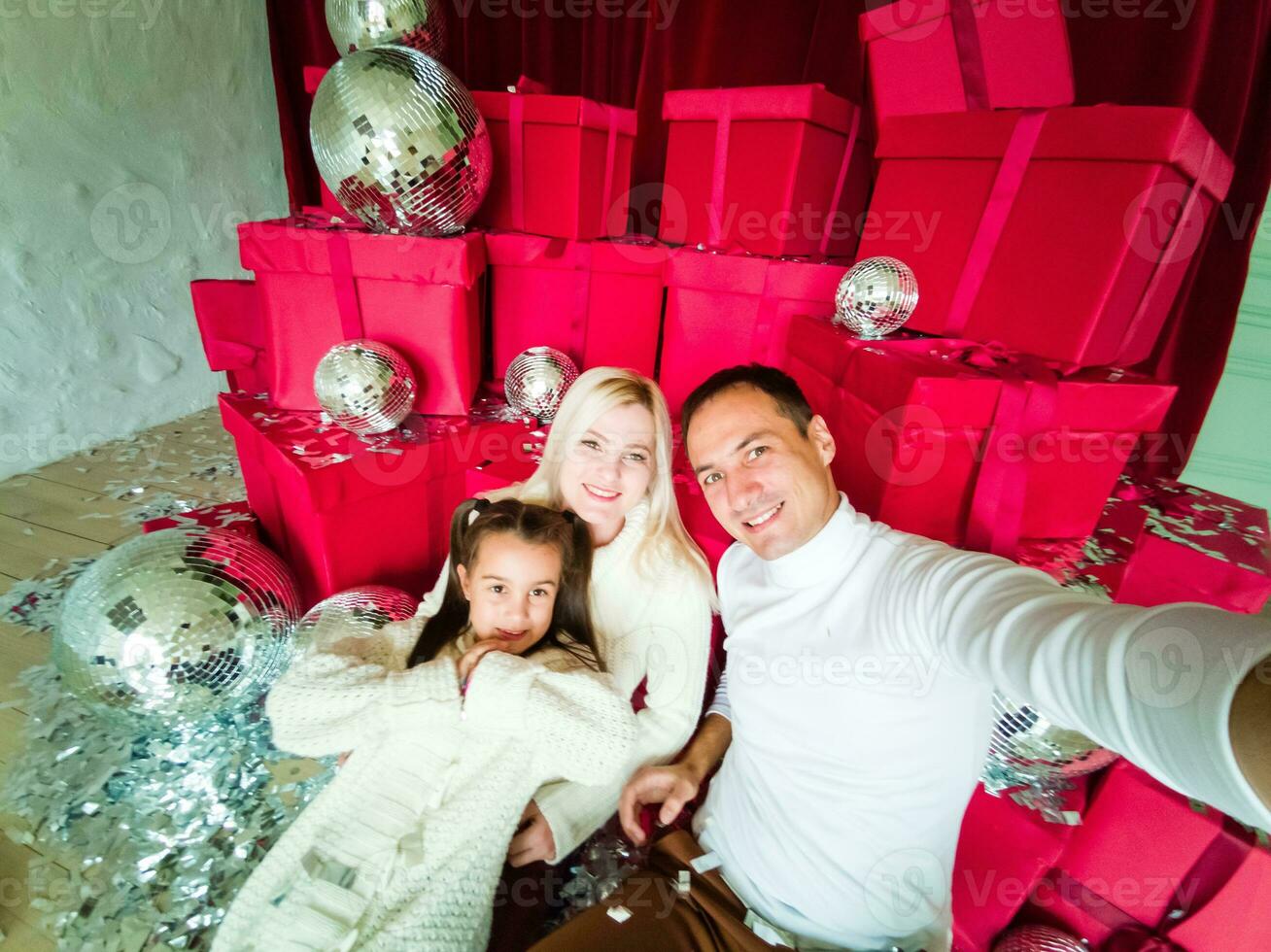 família, feriados, tecnologia e pessoas - sorridente mãe, pai e pequeno menina fazer selfie com Câmera sobre vivo quarto e Natal árvore fundo foto