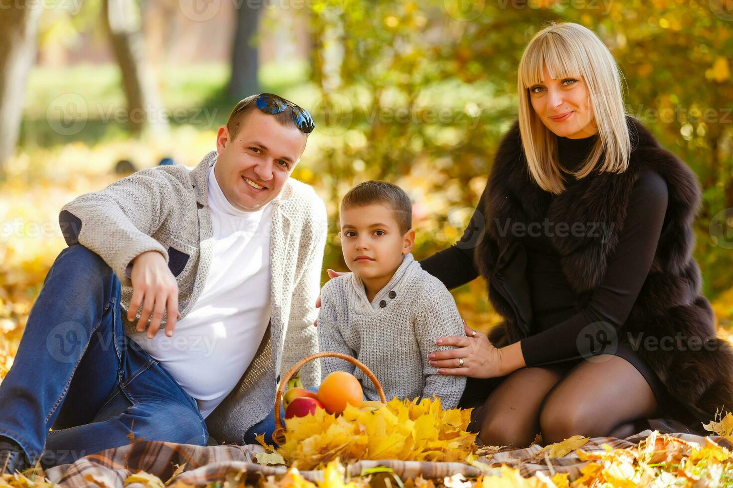feliz família do três deitado dentro a Relva dentro outono. caloroso efeito adicionado. foto