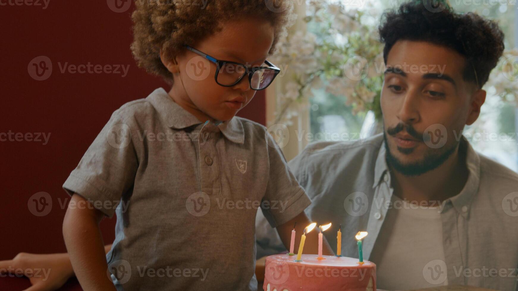 menino soprando velas no bolo com a família assistindo foto