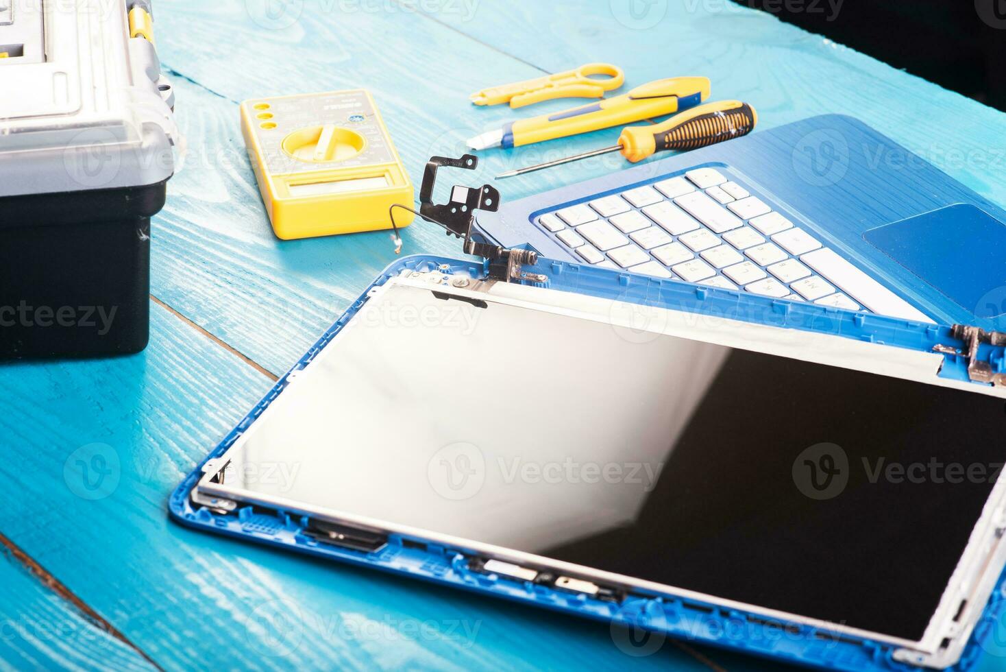 assistente repara laptop com ferramentas e mãos na mesa de madeira azul. vista do topo foto