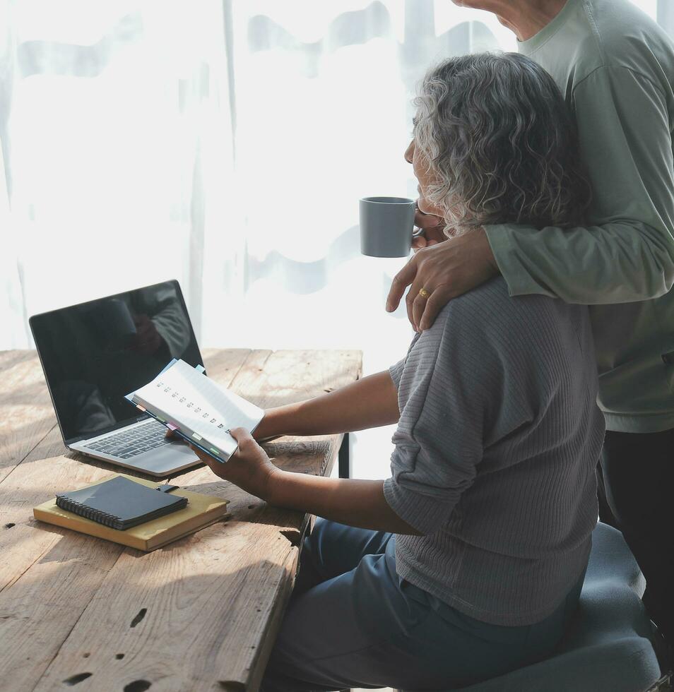 abraçado maduro casal surfar a Internet em computador portátil às casa foto