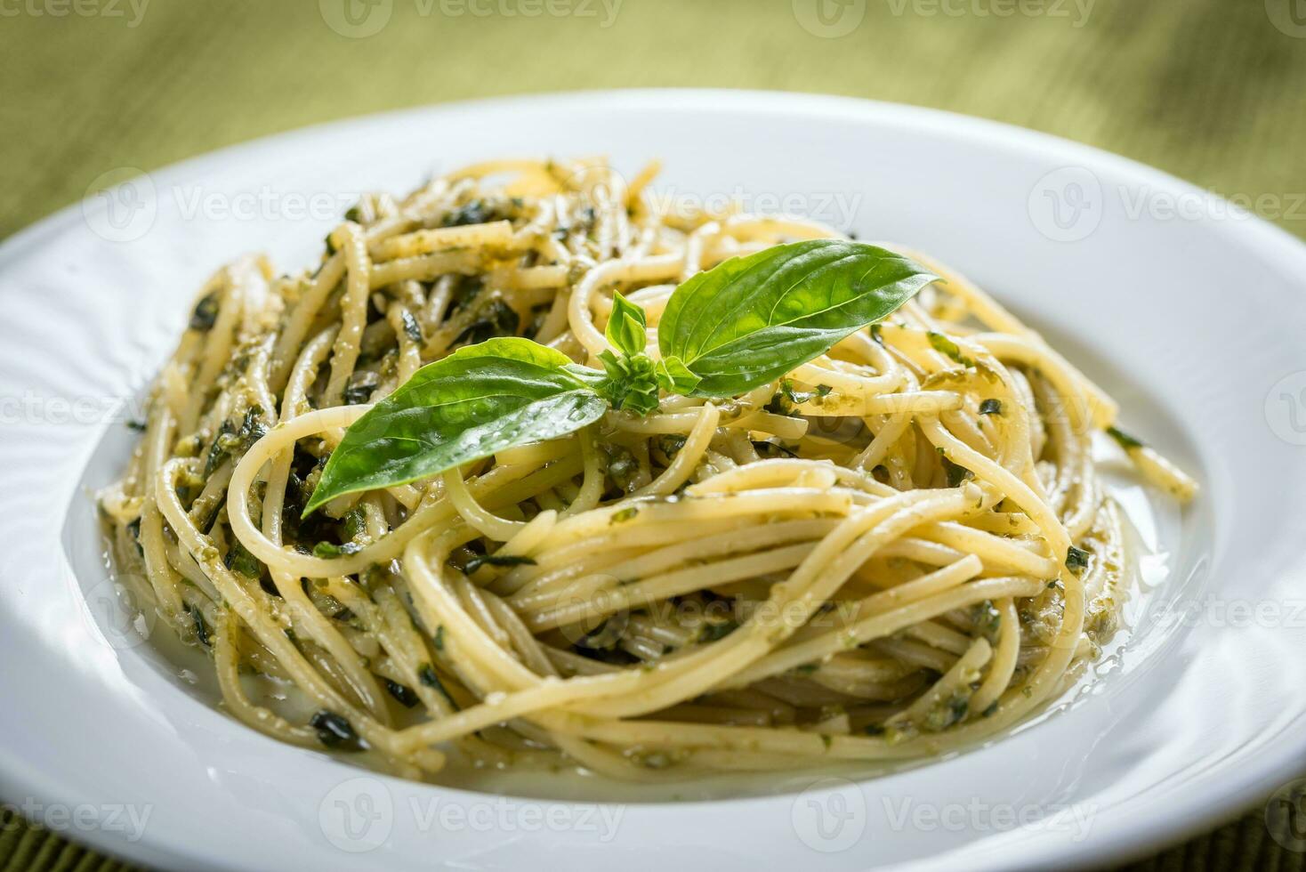 porção de macarrão com molho pesto e folha de manjericão foto