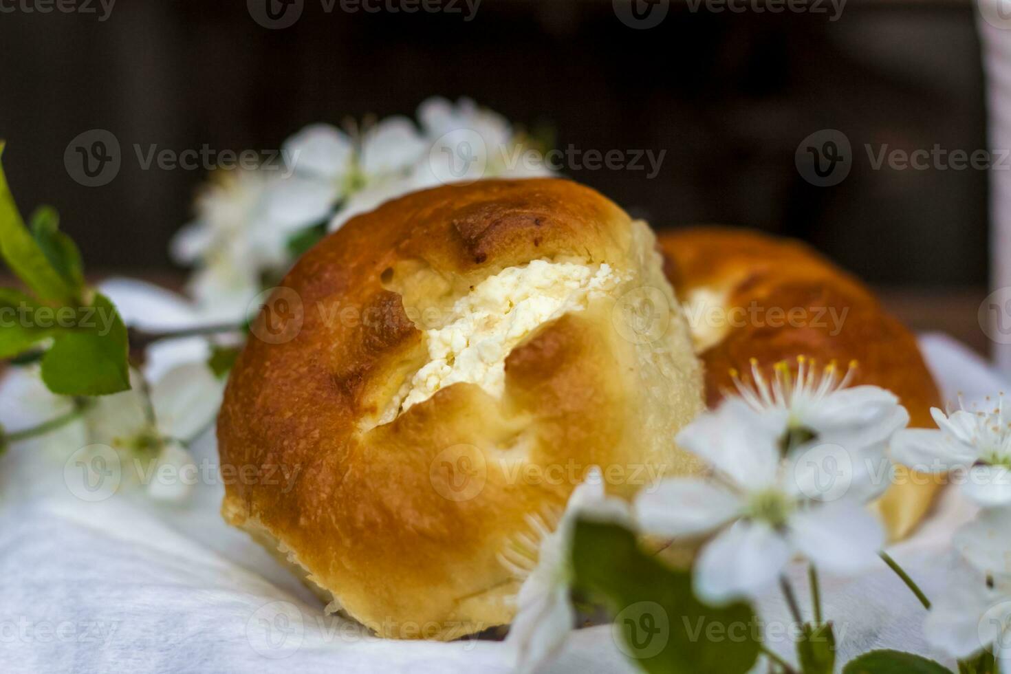 cozido aberto rolos e uma copo do café em uma escuro, desgastado rústico de madeira mesa. a composição é decorado com uma galho com branco flores cereja árvore flores seletivo foco. foto