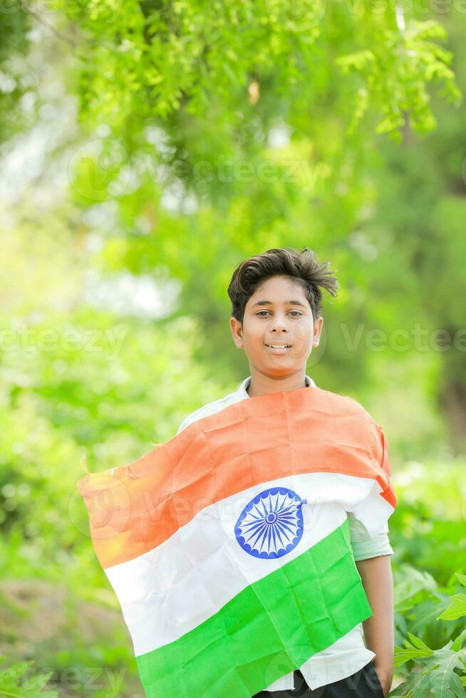 indiano Garoto segurando nacional bandeira dentro fazenda, feliz garoto, nacional bandeira foto