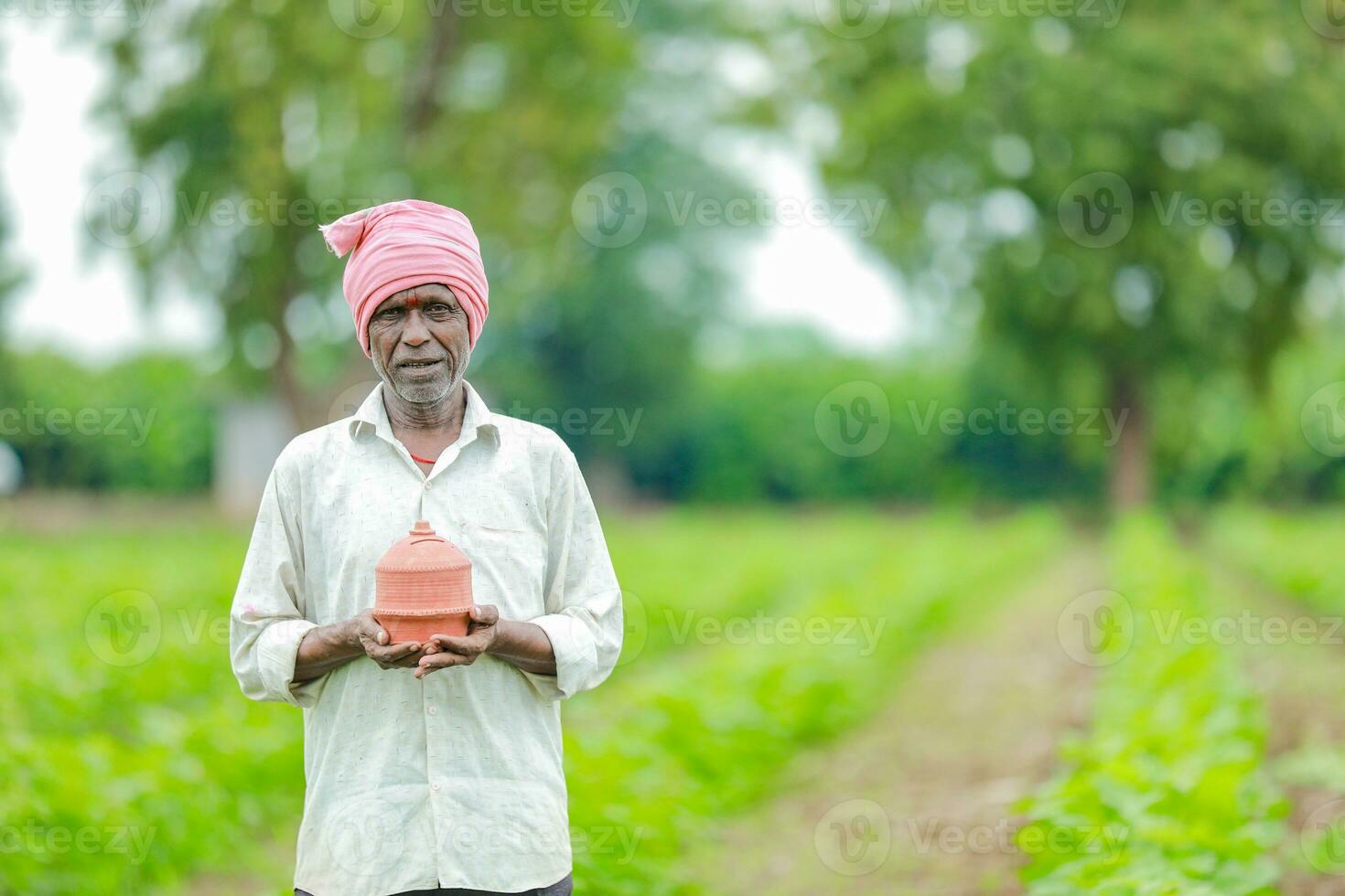 indiano agricultor segurando gullak dentro mão, salvando conceito, feliz pobre agricultor foto