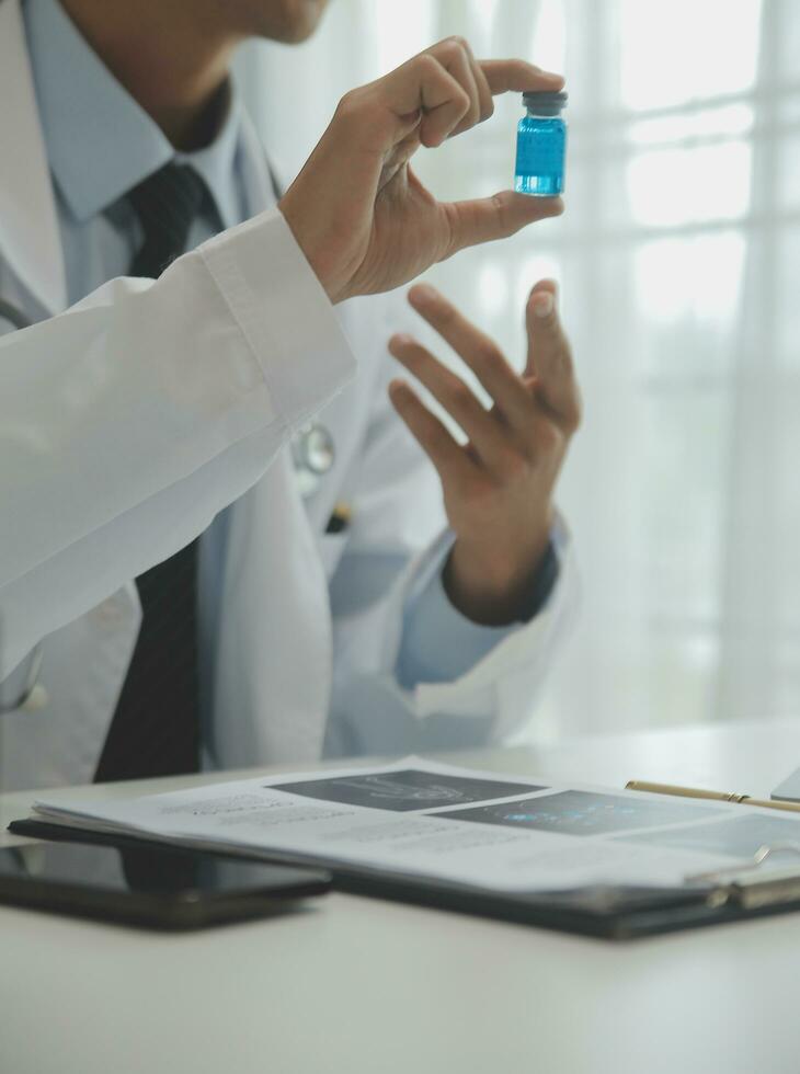 médico sentado às escrivaninha e escrevendo uma prescrição para dela paciente foto