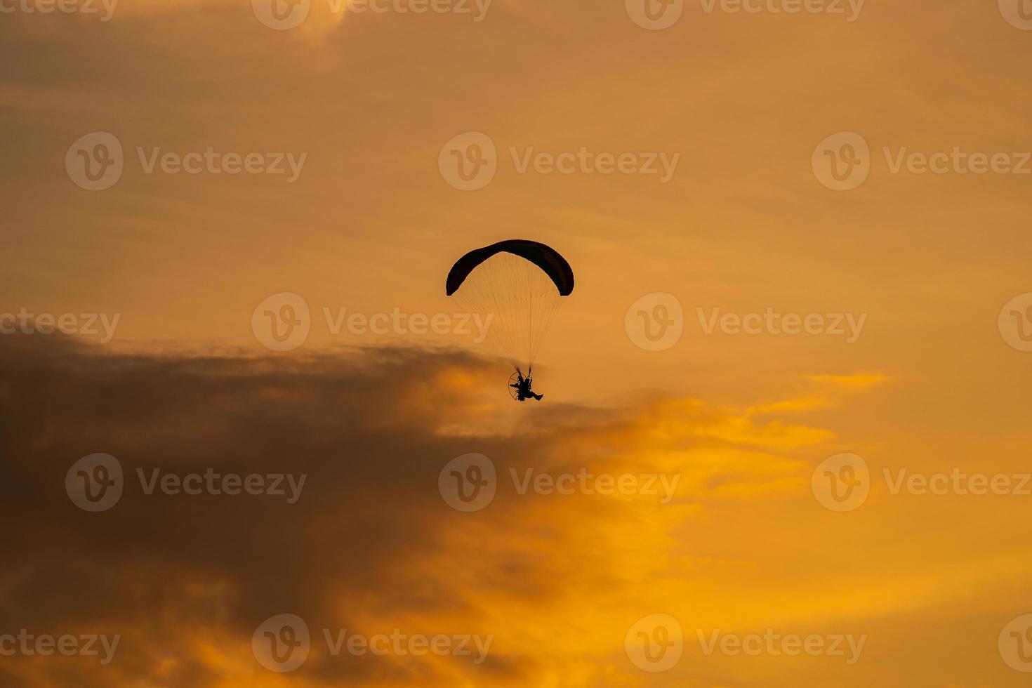 a silhueta do paramotor ao pôr do sol foto