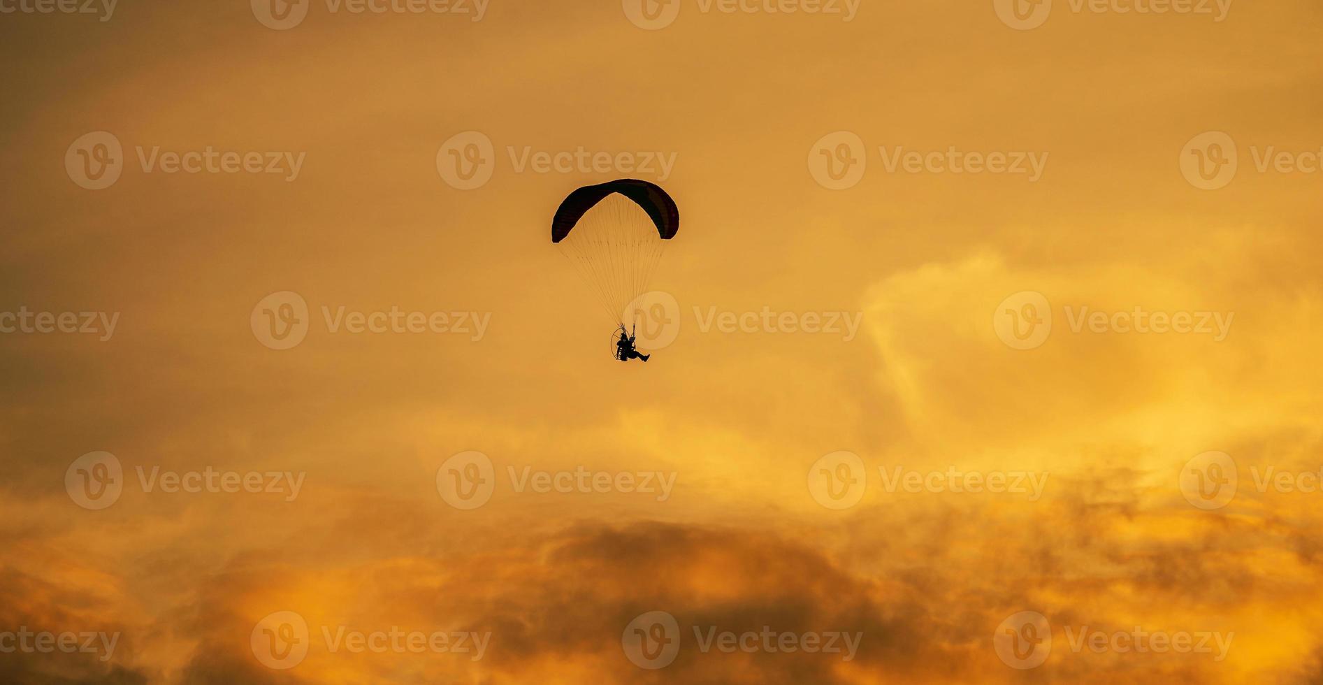 a silhueta do paramotor ao pôr do sol foto