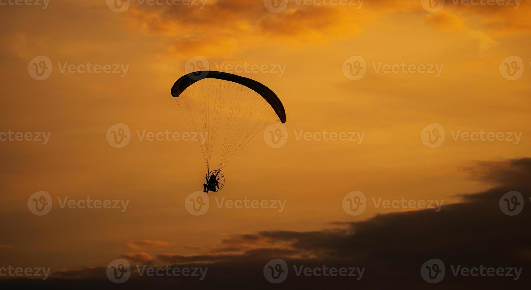 a silhueta do paramotor ao pôr do sol foto