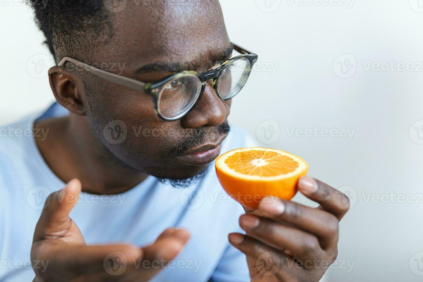 doente aricano homem tentando para sentido cheiro do metade fresco laranja, tem sintomas do COVID-19, corona vírus infecção - perda do cheiro e gosto. 1 do a a Principal sinais do a doença. foto