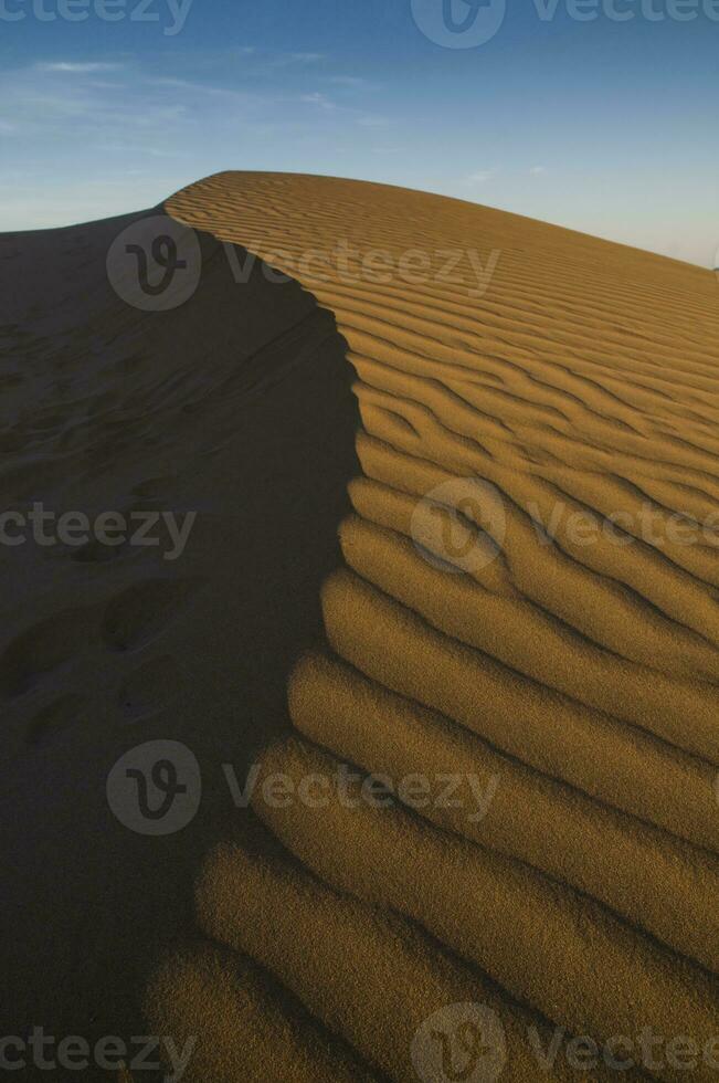 uma deserto com areia dunas e uma azul céu foto