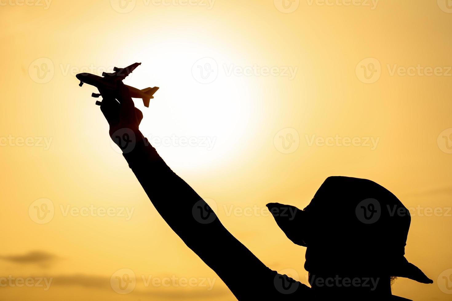 silhueta de uma mão segurando o modelo do avião no colorido dramático céu ao pôr do sol foto