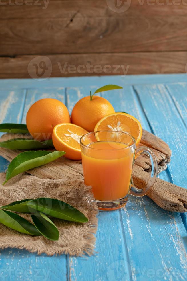 laranja fresca e um copo de suco de laranja no fundo da mesa de madeira foto