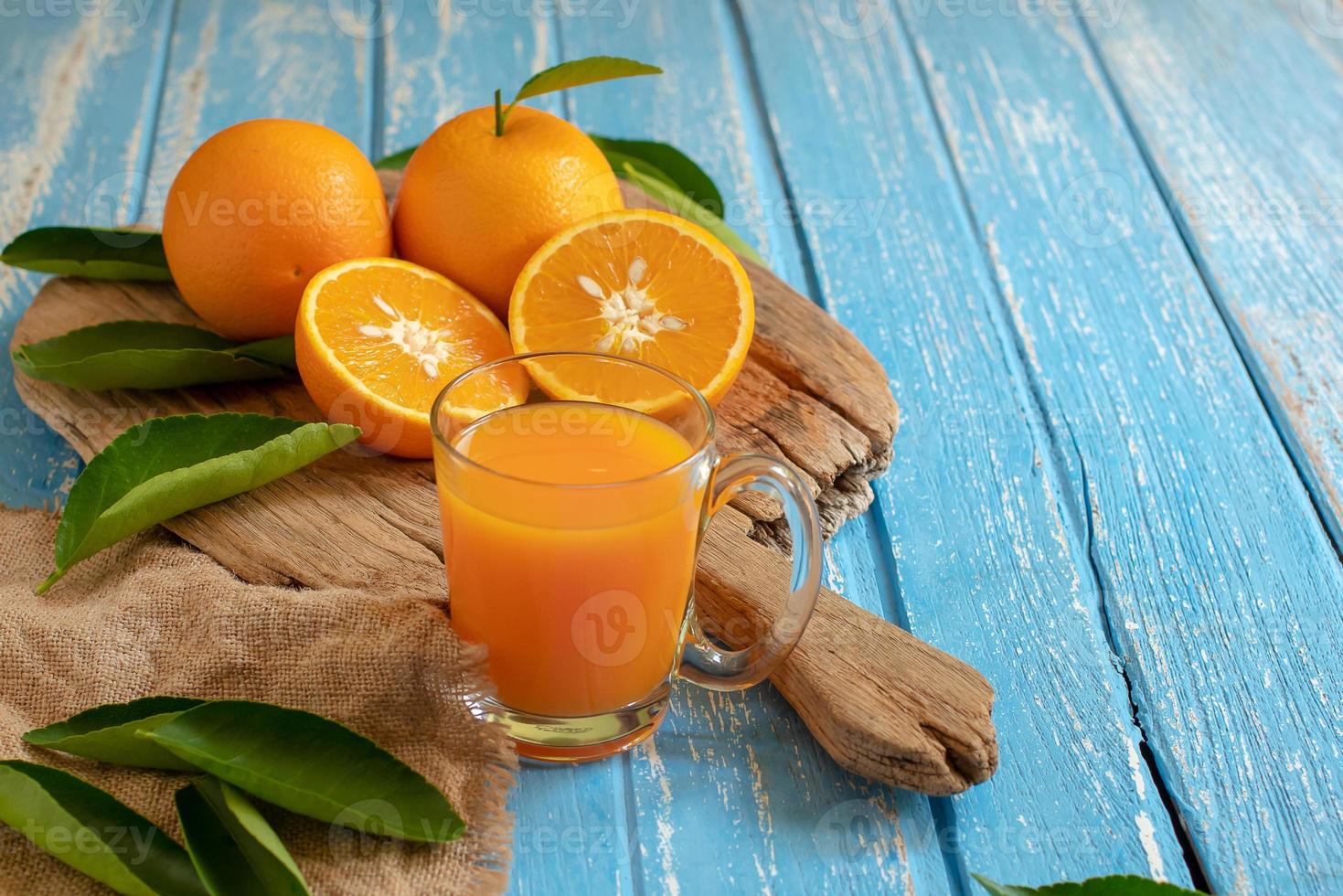 laranja fresca e um copo de suco de laranja no fundo da mesa de madeira foto